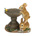 Solar bird bath and feeder with three rabbit figurines beside a round bowl
