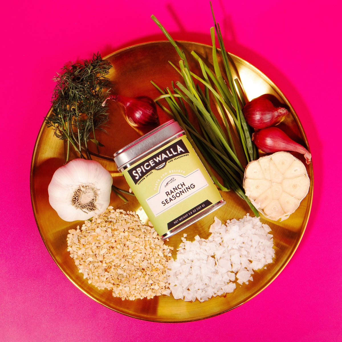 Ranch seasoning jar with green label and silver lid, surrounded by herbs and spices.