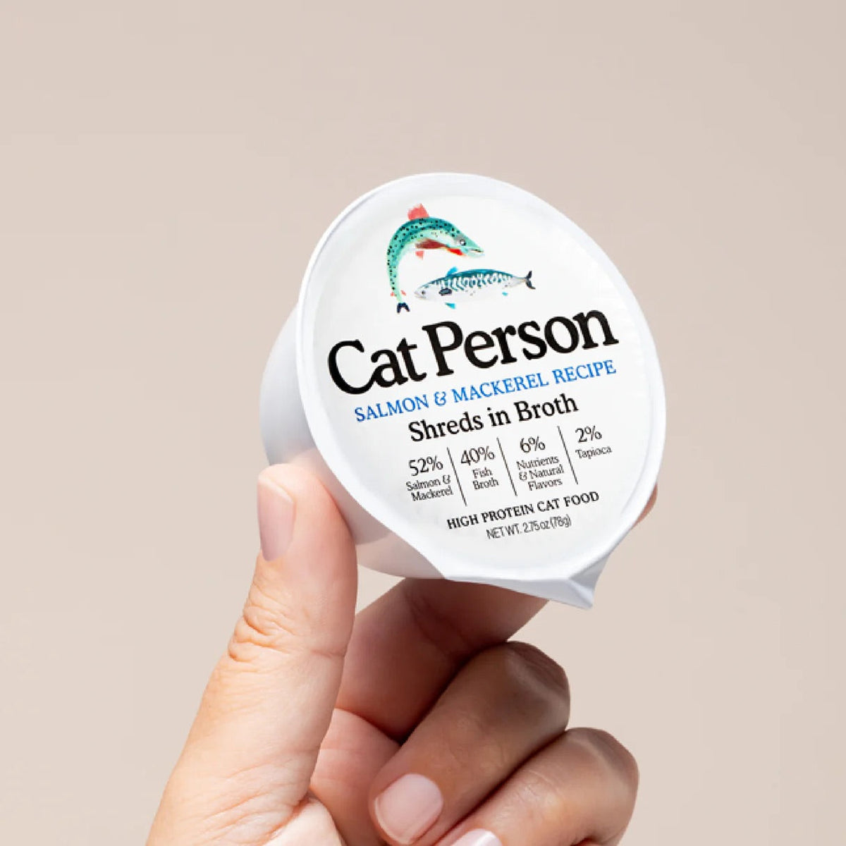 Cat Person shredded salmon & mackerel cat food cup in broth, held in hand