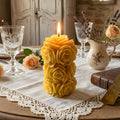 Yellow rose-shaped beeswax candle with layered petals and a lit wick
