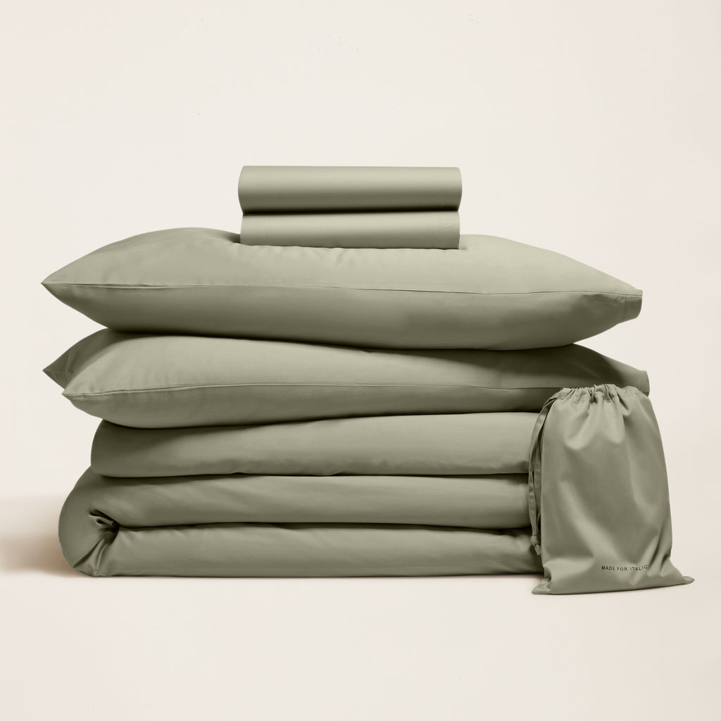 Green sateen bedding bundle with stacked sheets, pillowcases, and folded top sheet
