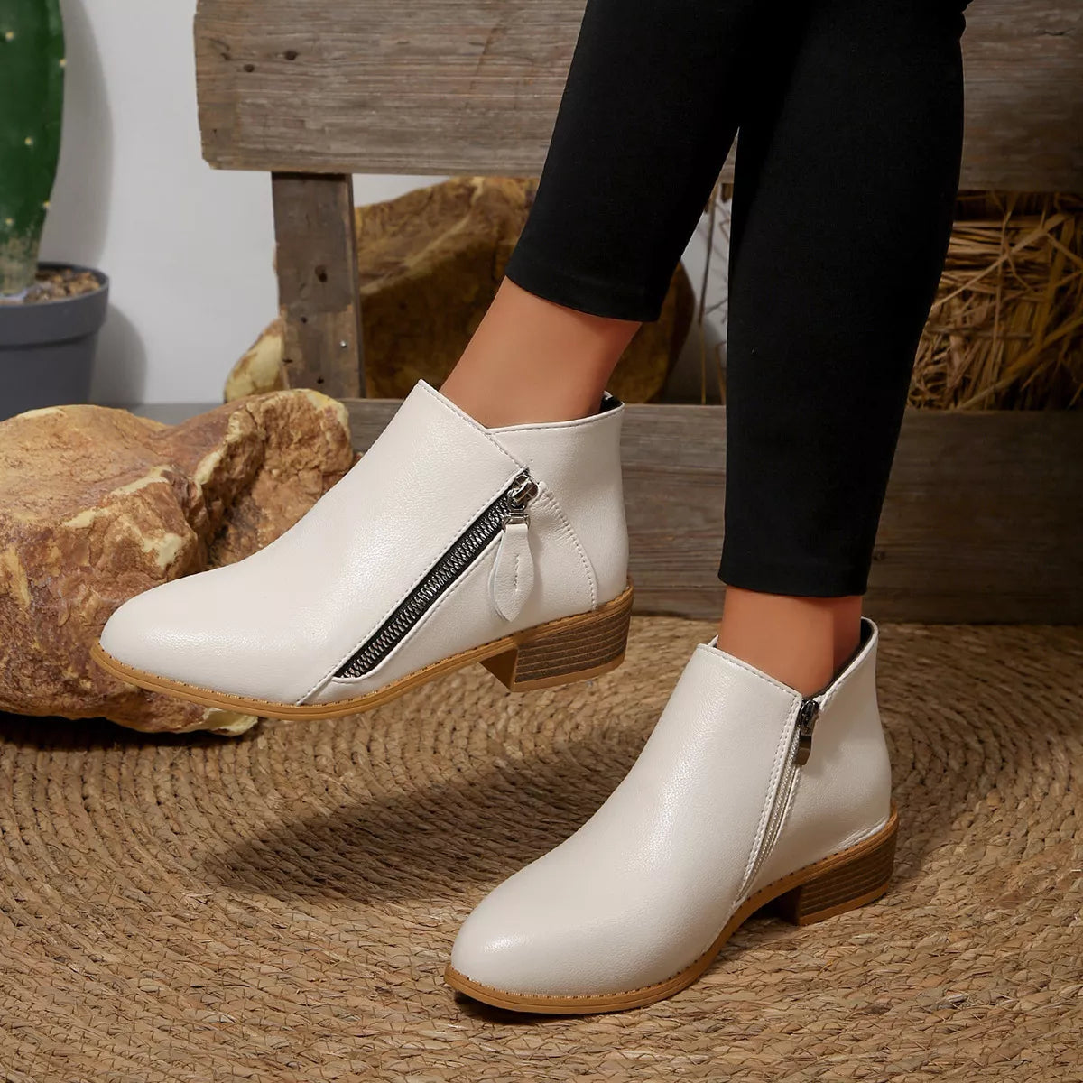 White ankle boots with side zipper and block heel, shown with black pants