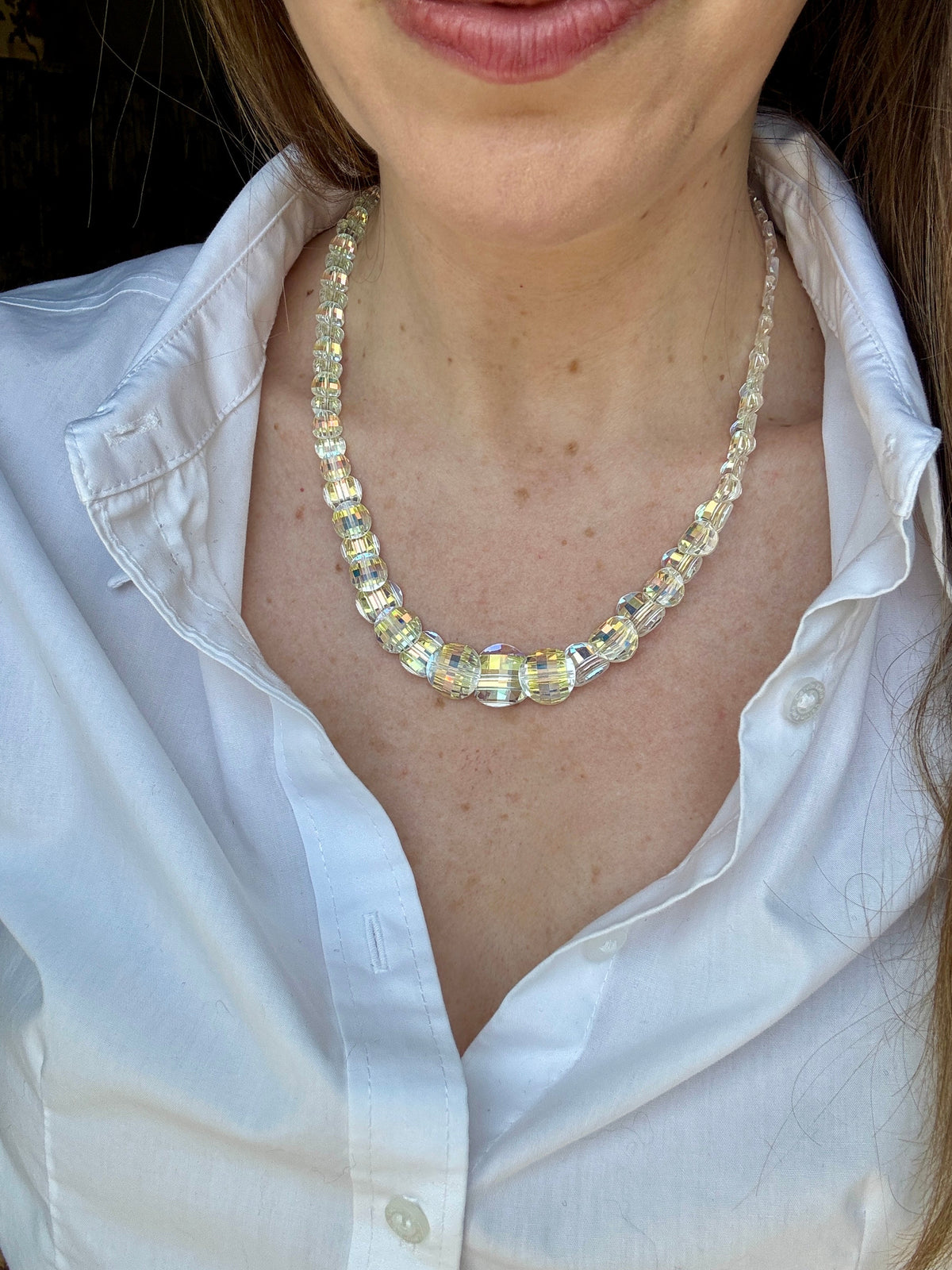 Iridescent faceted crystal bead necklace worn with open white blouse
