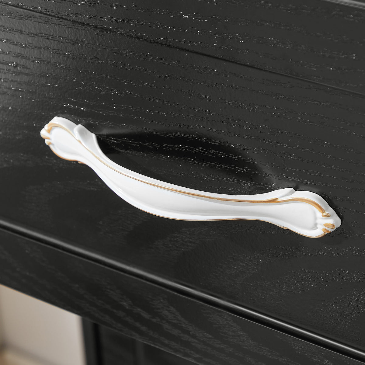 Close-up of white and gold metal drawer pull on a black dresser