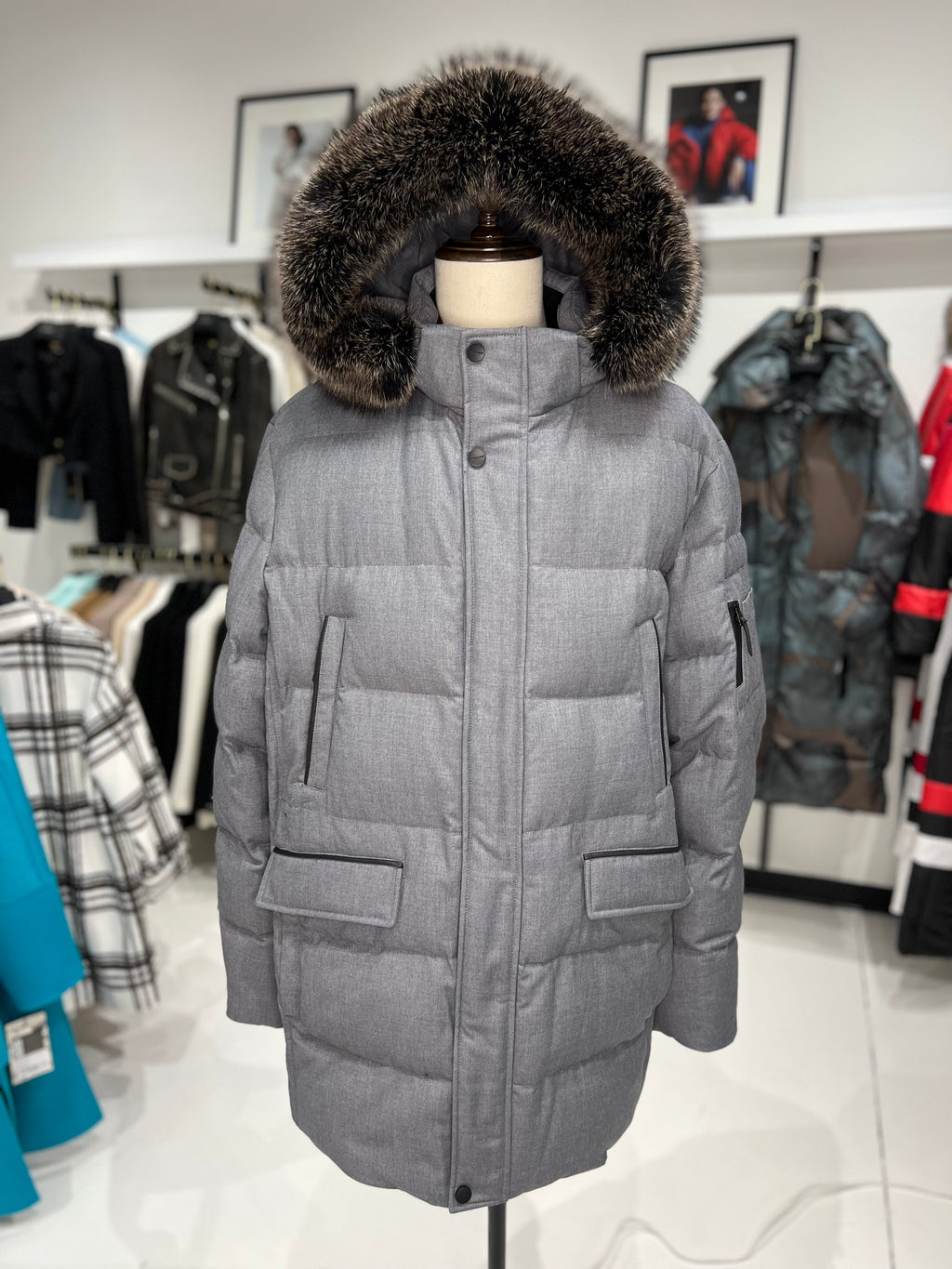 Grey long puffer coat on display with faux fur hood trim and front patch pockets