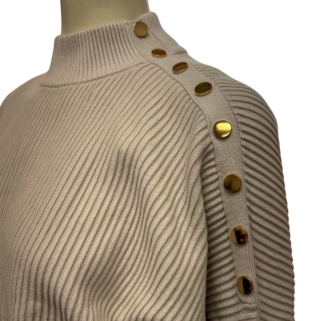 Close-up of beige mock neck knit sweater with gold button shoulder placket