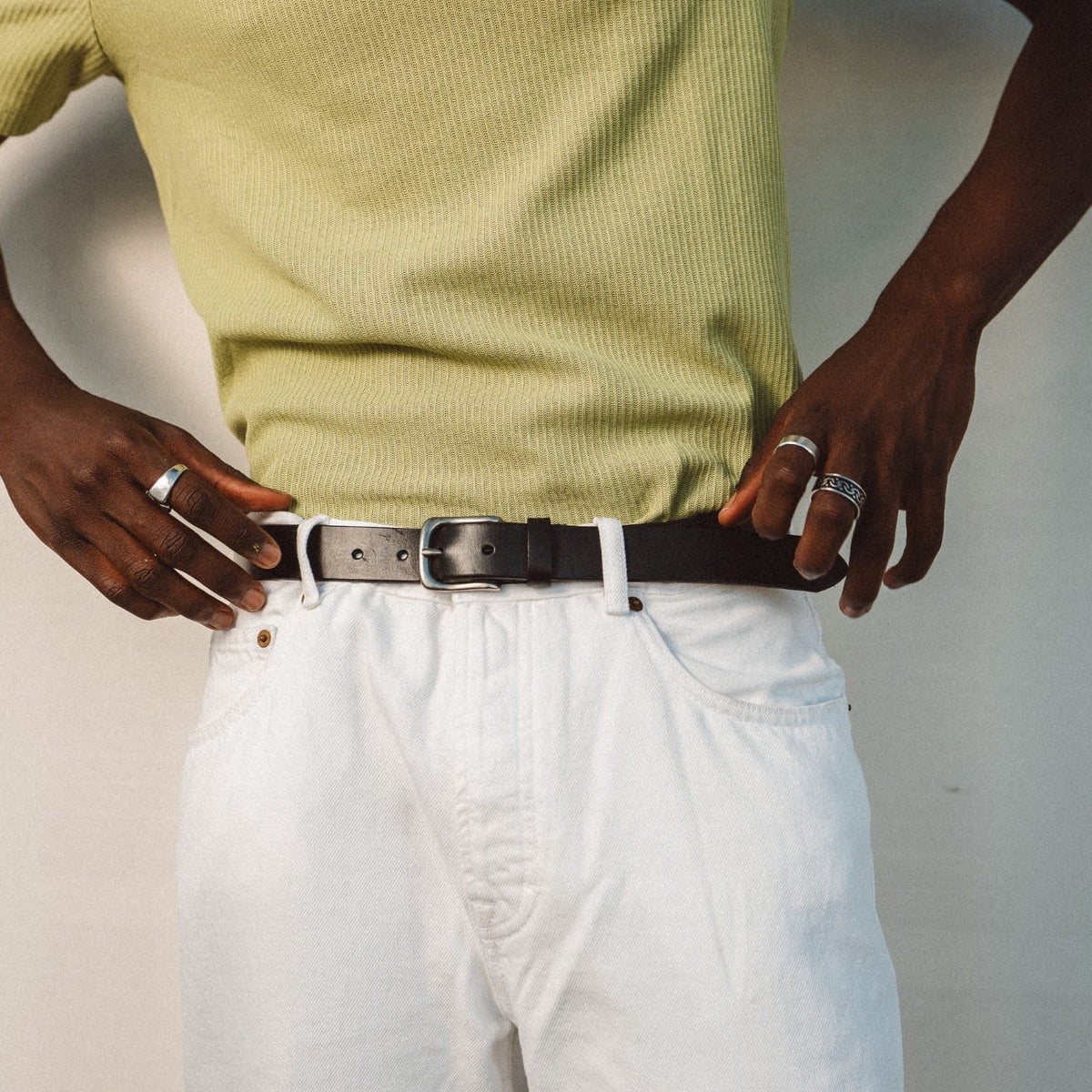 Black leather belt with silver buckle on white pants