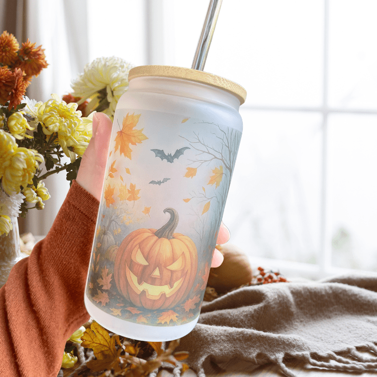 Frosted pumpkin-themed iced drink cup with straw and autumn foliage and bats