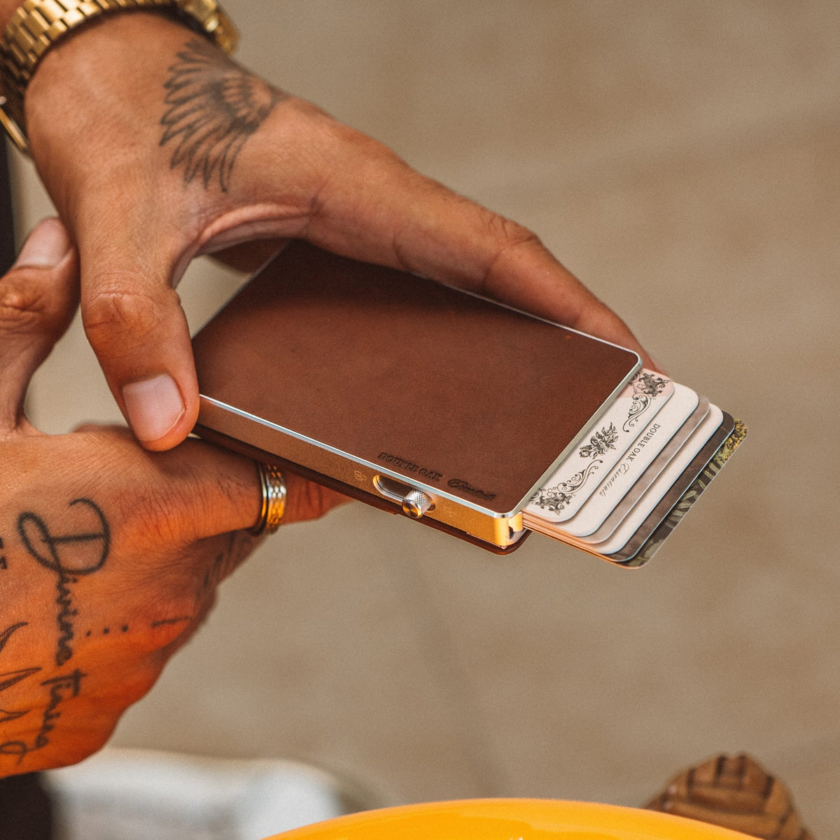 Brown leather cardholder wallet open showing cards and metal hinge, angled side view