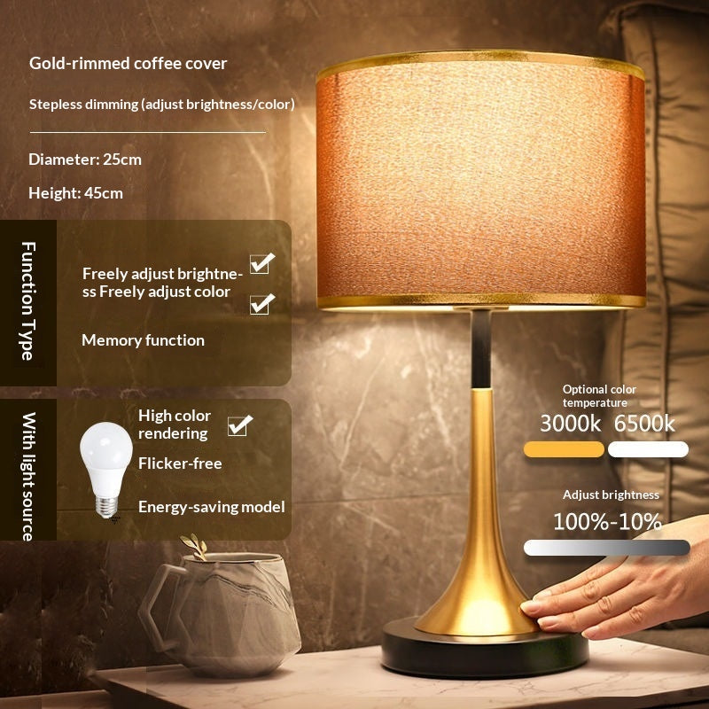 Gold table lamp with orange-gold fabric shade and gold base with dark round foot