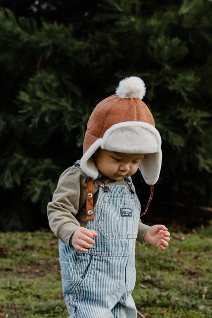 Kids faux suede trapper hat with white sherpa lining and pom-pom, tan trim ear flaps