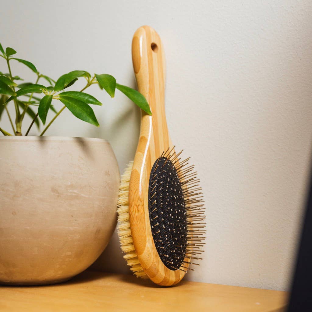Bamboo pet grooming brush with black oval rubber pad and mixed bristles, wood handle