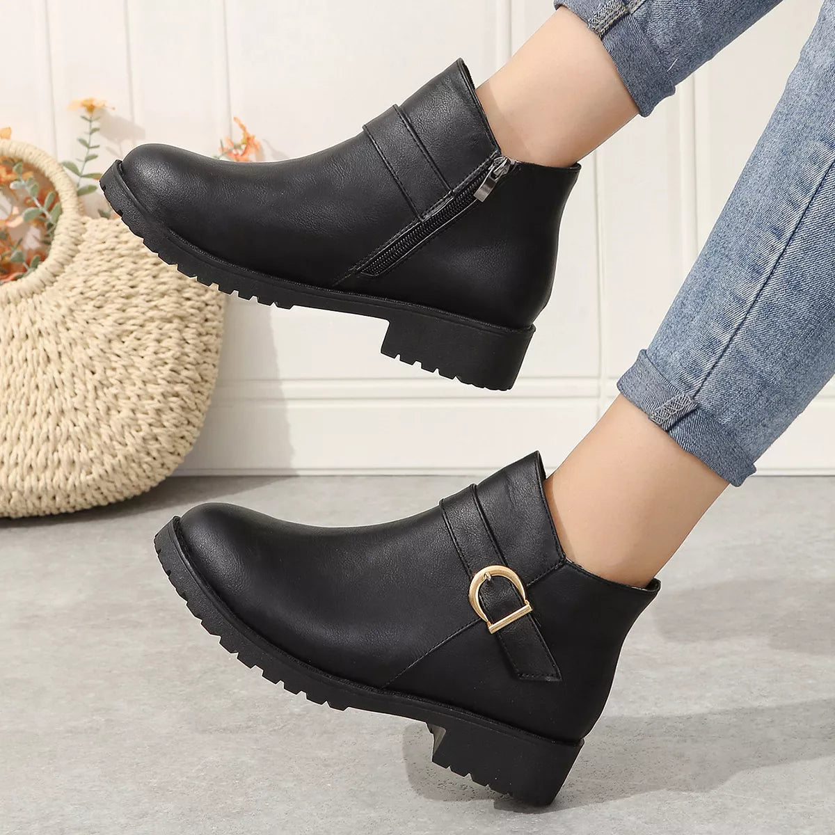 Black ankle boots with buckle strap and side zipper, thick outsole and low heel.