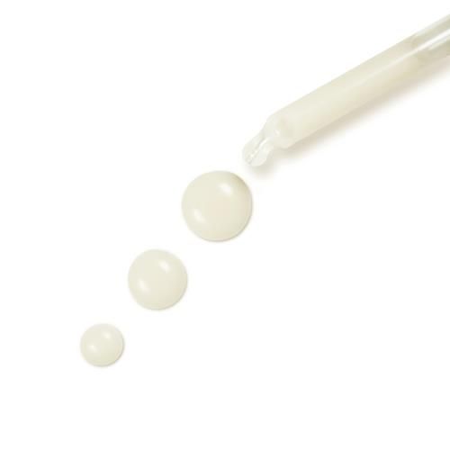 Serum dropper releasing pale cream drops