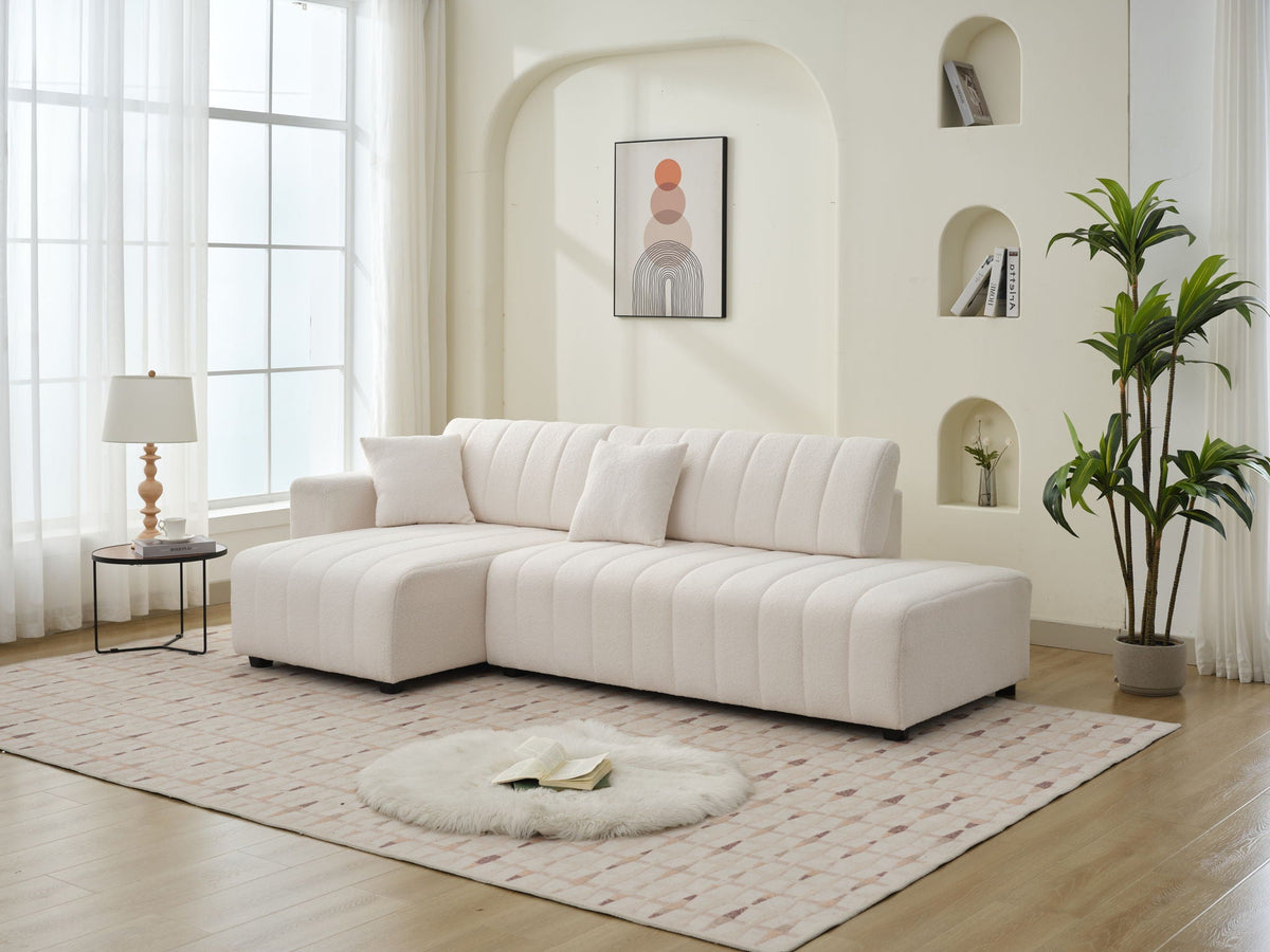 Beige lamb-wool sectional sofa with chaise, left-arm facing; plush tufted cushions.