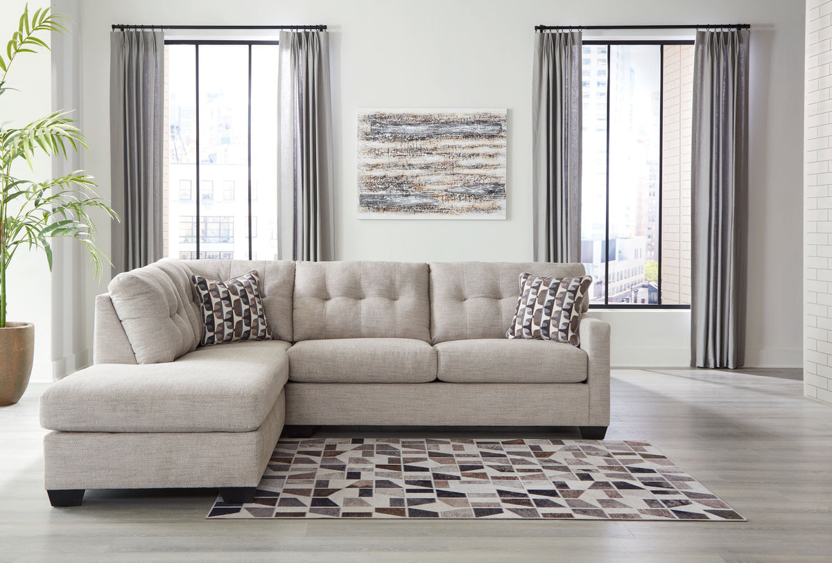 Light gray corner chaise sectional with tufted cushions and patterned throw pillows