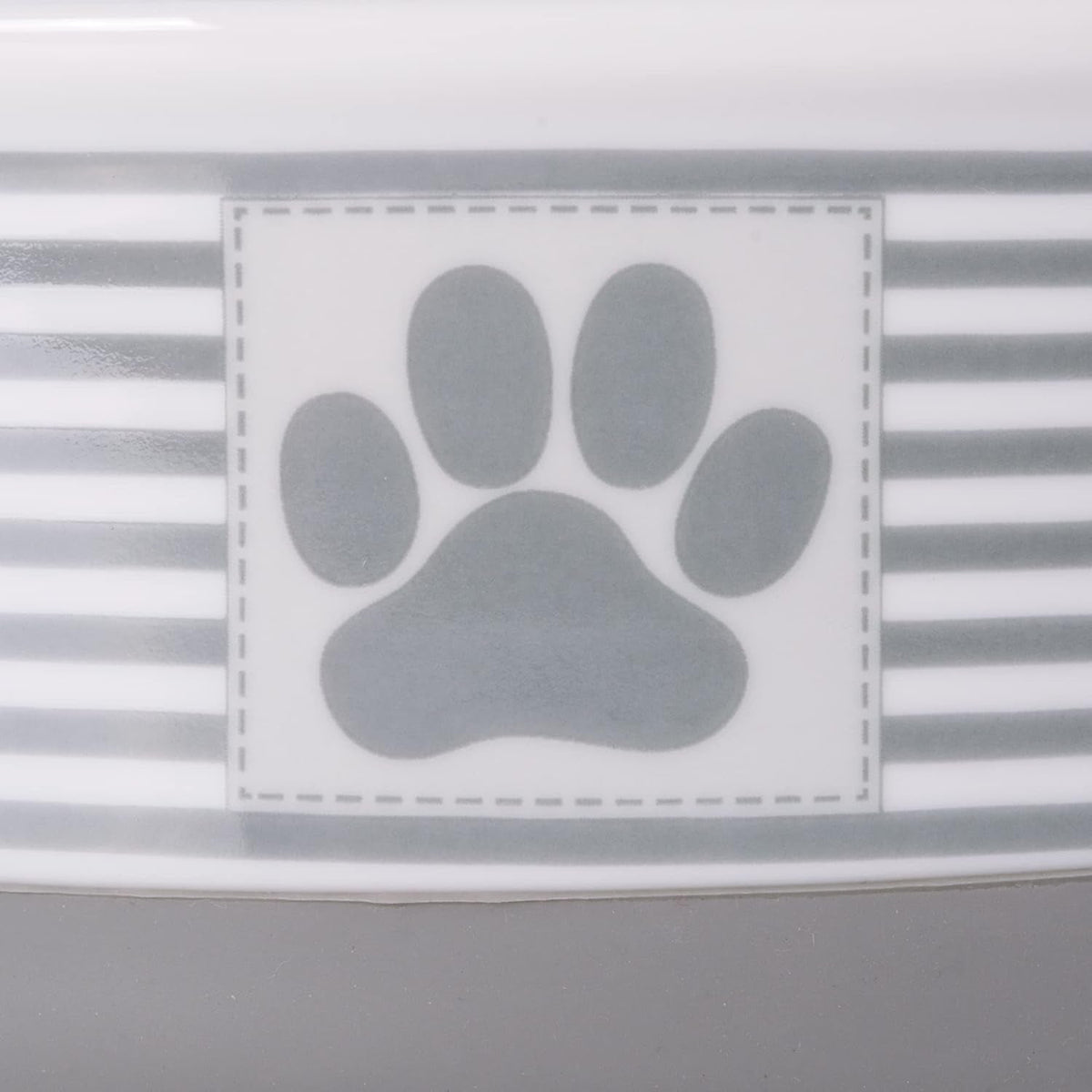 Close-up of gray paw-print badge on a striped ceramic pet bowl