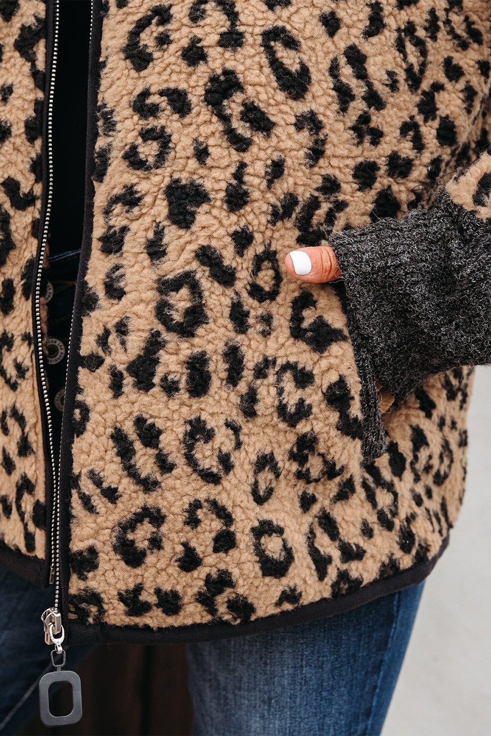 Leopard-print fleece jacket detail: front zipper and dark side pocket with black trim.