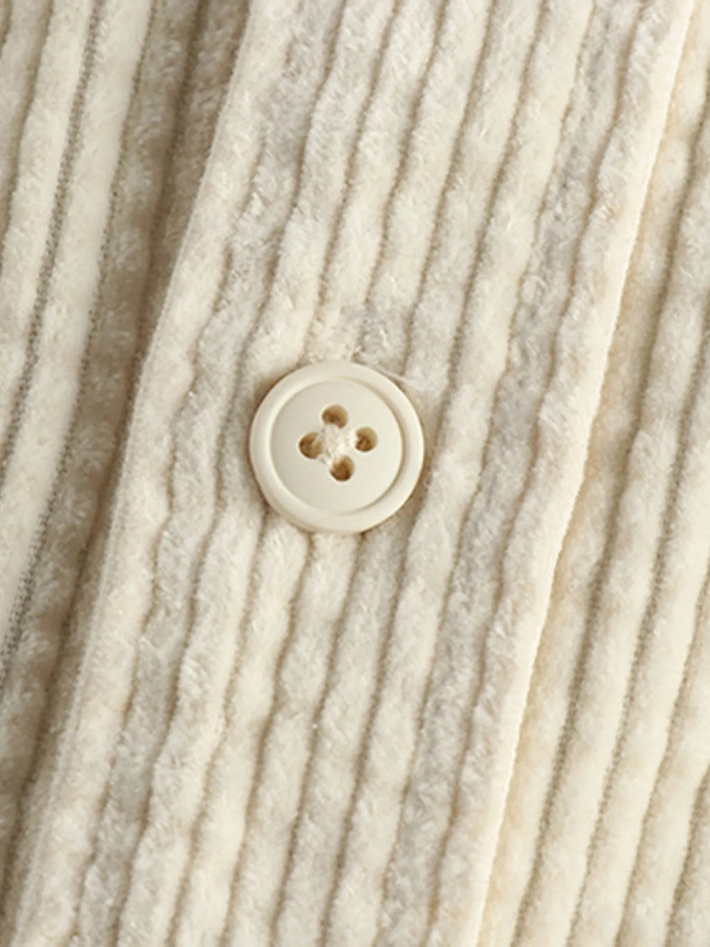 Close-up of light beige corduroy shirt front button near the collar