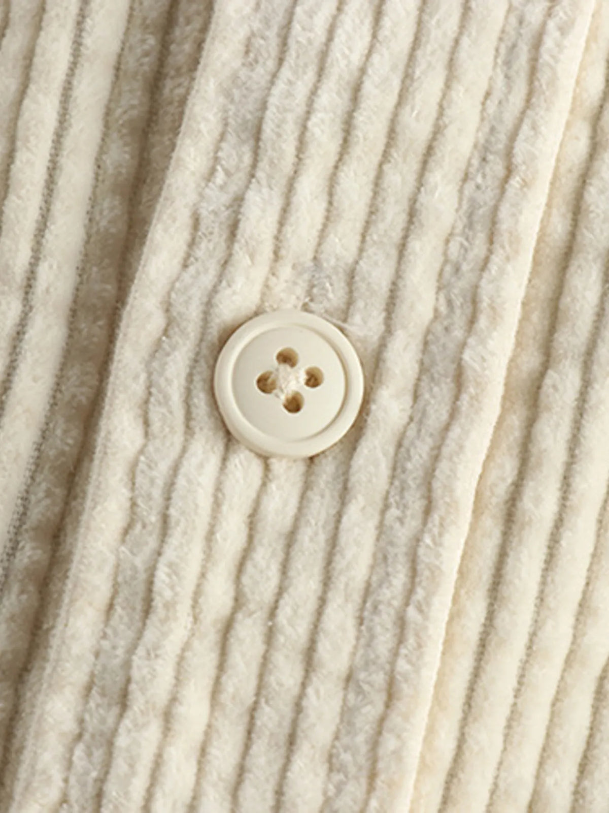 Close-up of light beige corduroy shirt front button near the collar