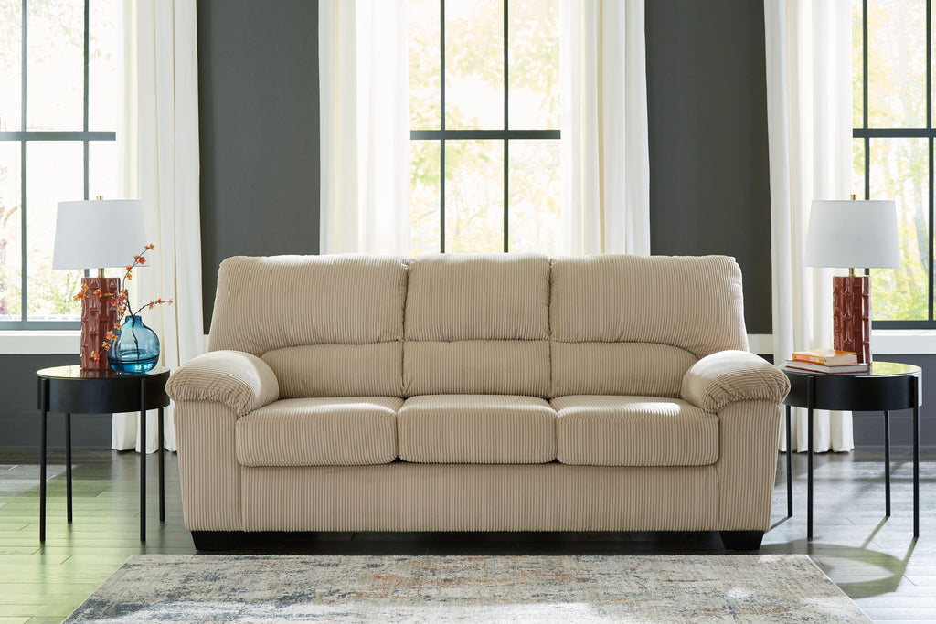 Light beige sofa with rolled arms, tufted back cushions, and three seat pads