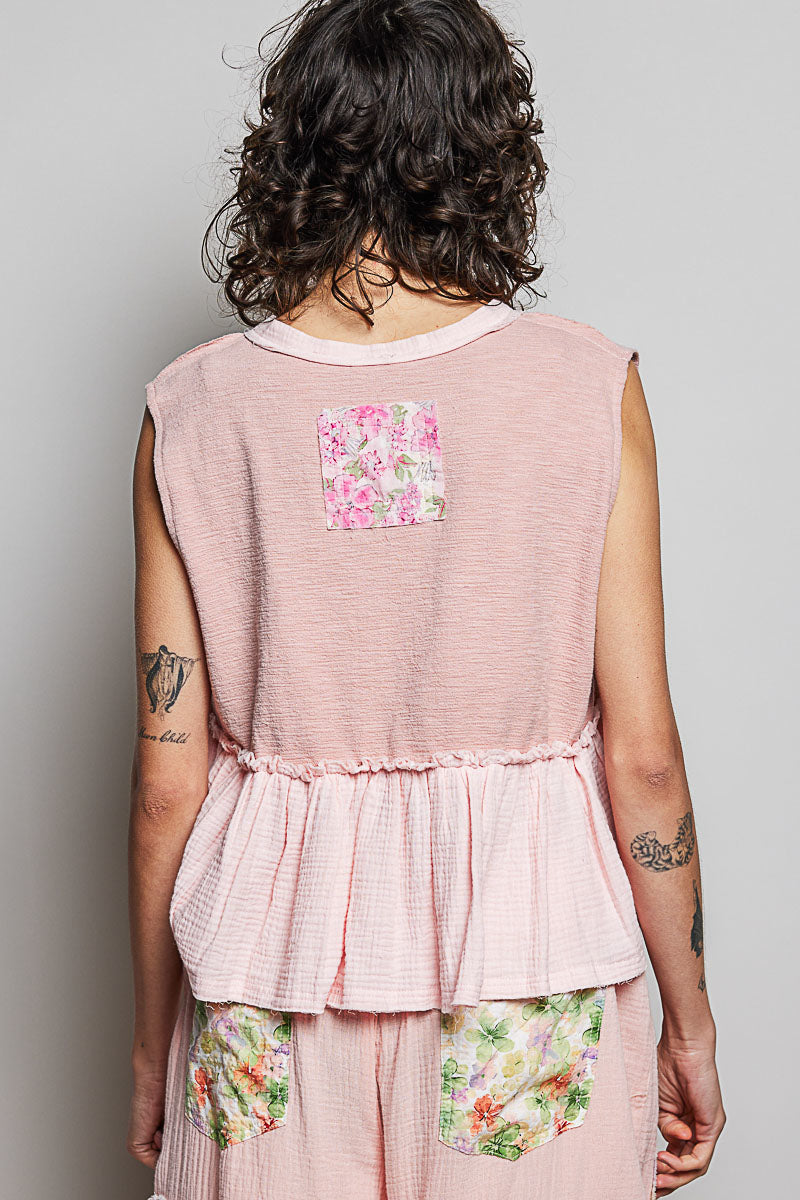 Back view of pink sleeveless top with floral patch detail and ruffled peplum hem