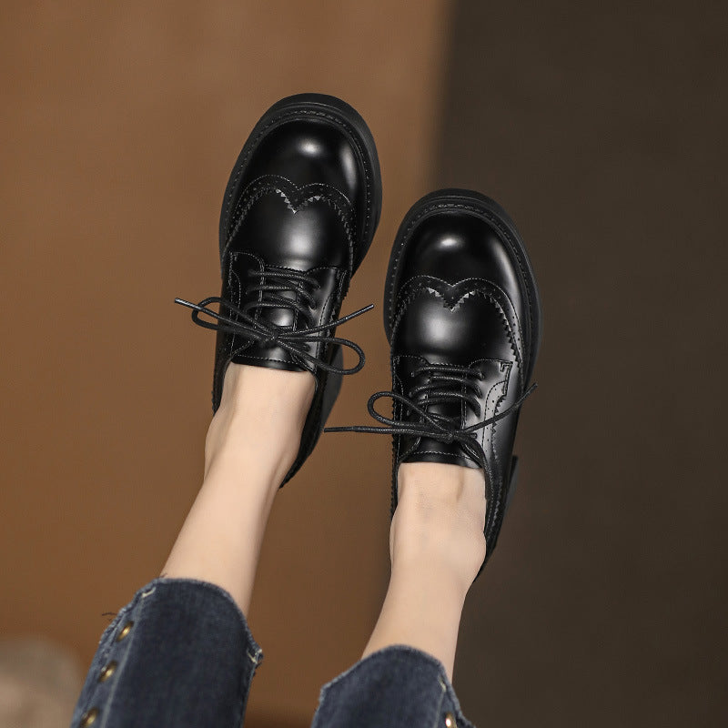 Pair of black lace-up shoes with rounded toe and decorative stitched panels.