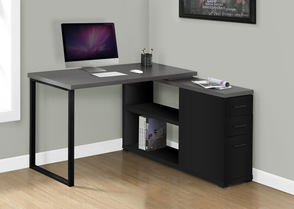 Gray L-shaped computer desk with open cubby and three drawer storage on right