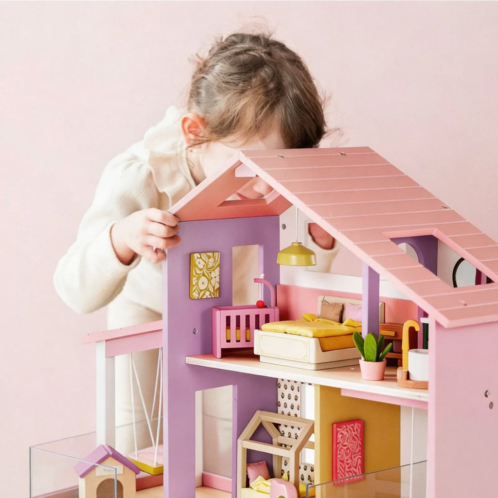Pink dollhouse roof and upper room with bed, lamp, and window details