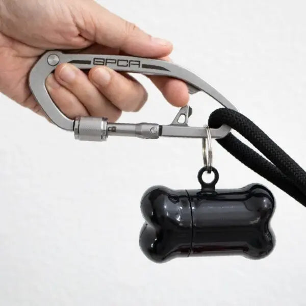 Dog leash clip with gray top bar and black strap, with attached black bone tag.
