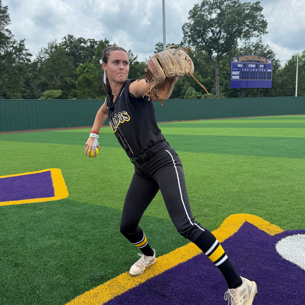 Softball training grip on glove hand holding a neon ball outdoors