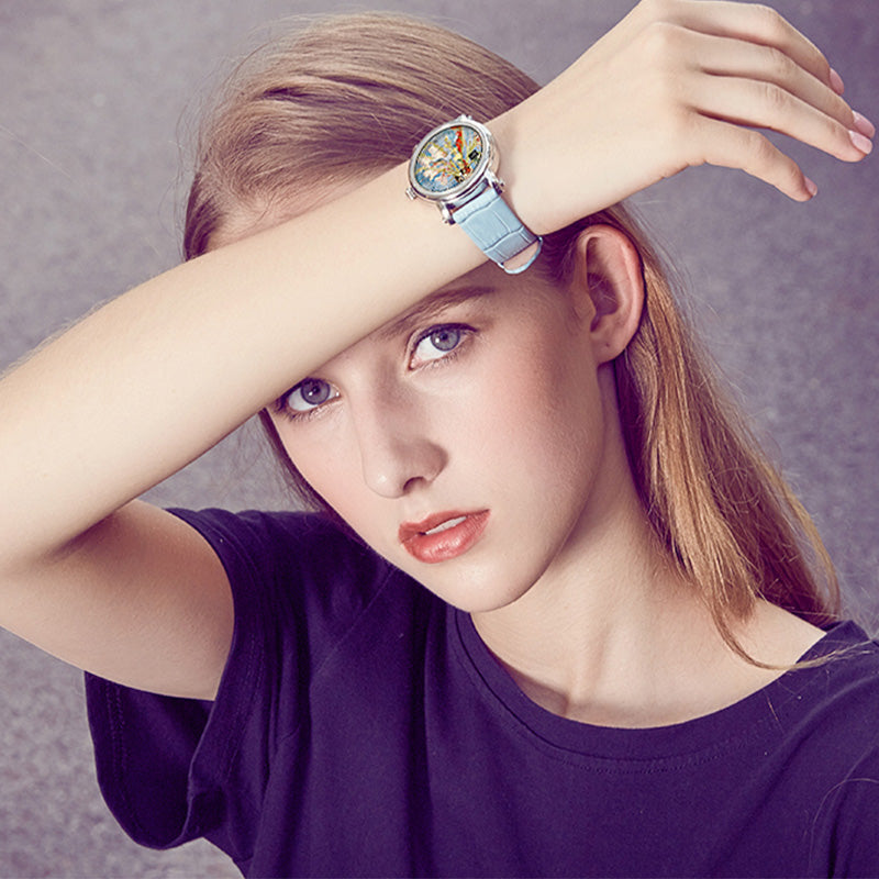 Quartz wristwatch on wrist with blue strap and rose-gold case, round colorful art dial