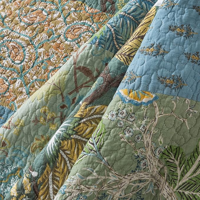 Quilt close-up showing blue, green, and gold stitched leaf and flower patchwork