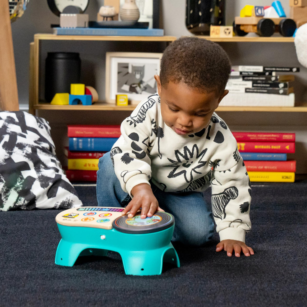Young child playing with teal and wood toddler discovery stool with picture button dial