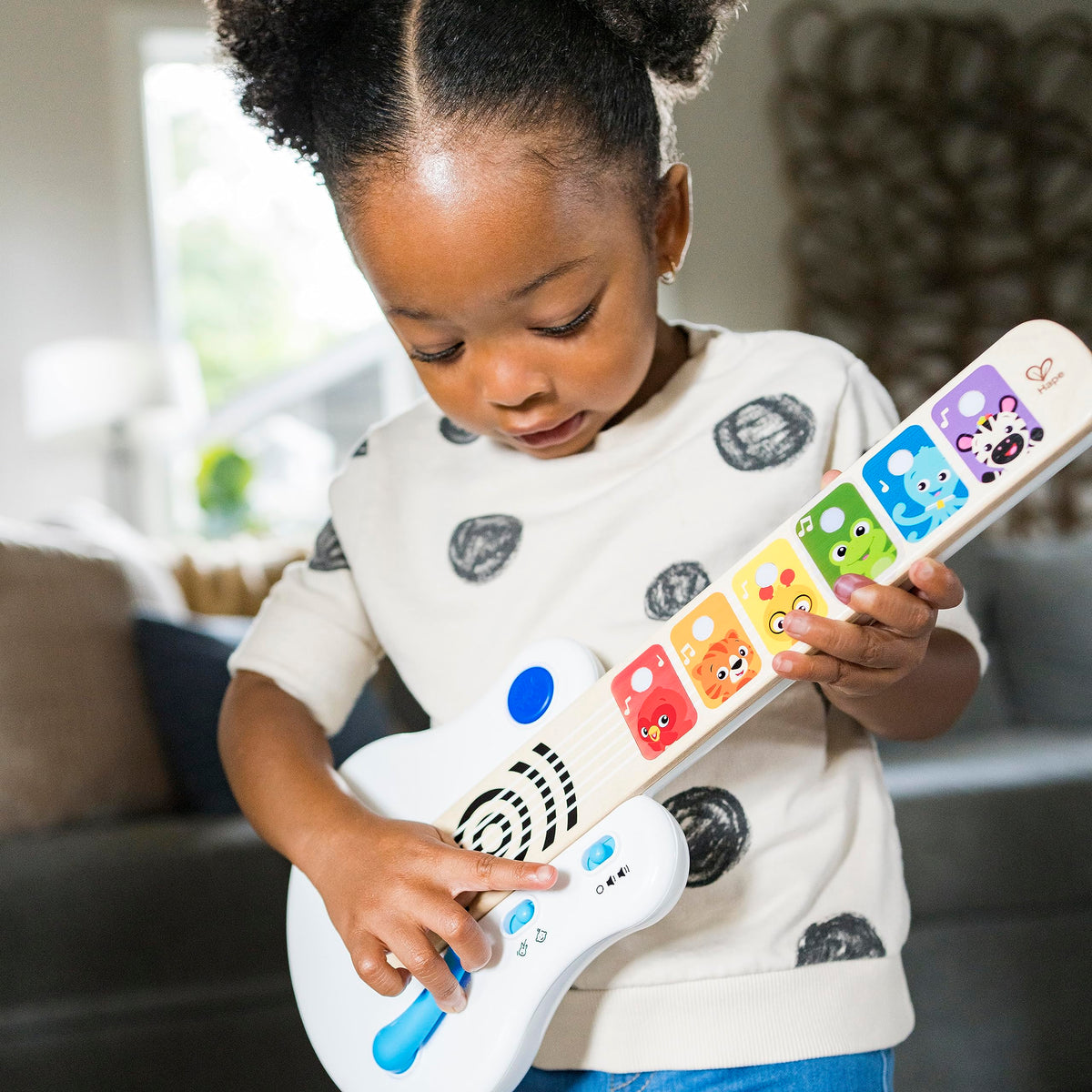 Child holding a light-up wooden guitar with animal fretboard and blue strum controls