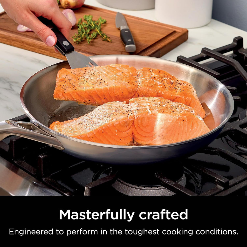 Stainless steel frying pan on gas cooktop with seasoned salmon fillets