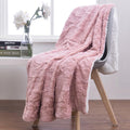 Dusty pink faux fur throw blanket with white sherpa-style reverse edge, draped