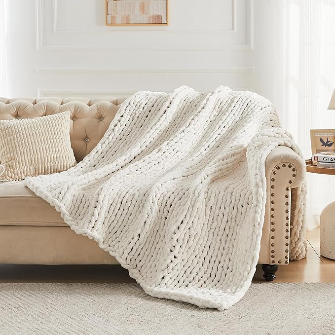 Cream chunky knit throw blanket draped over sofa, thick loop cable texture