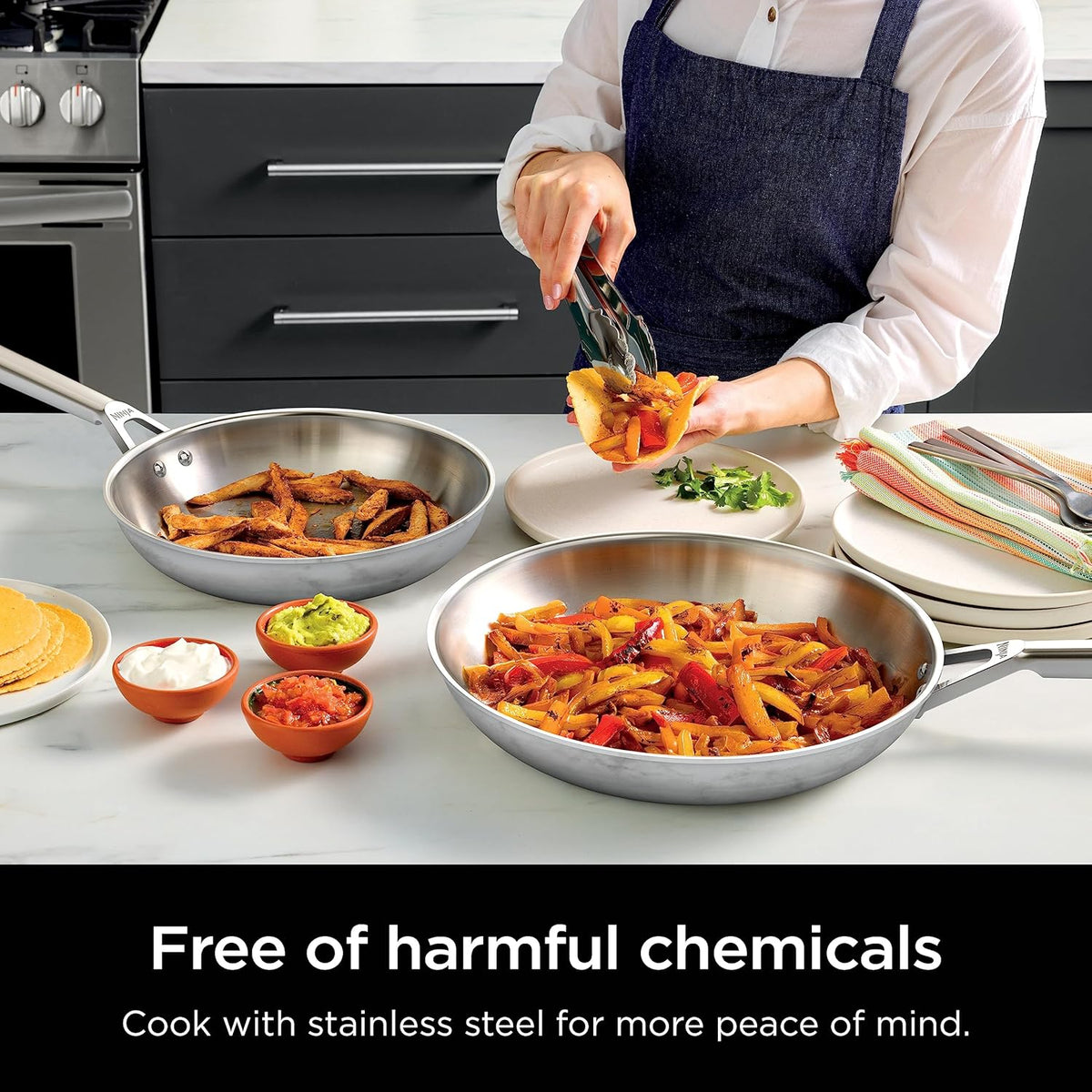 Stainless steel frying pans filled with cooked penne on a kitchen counter