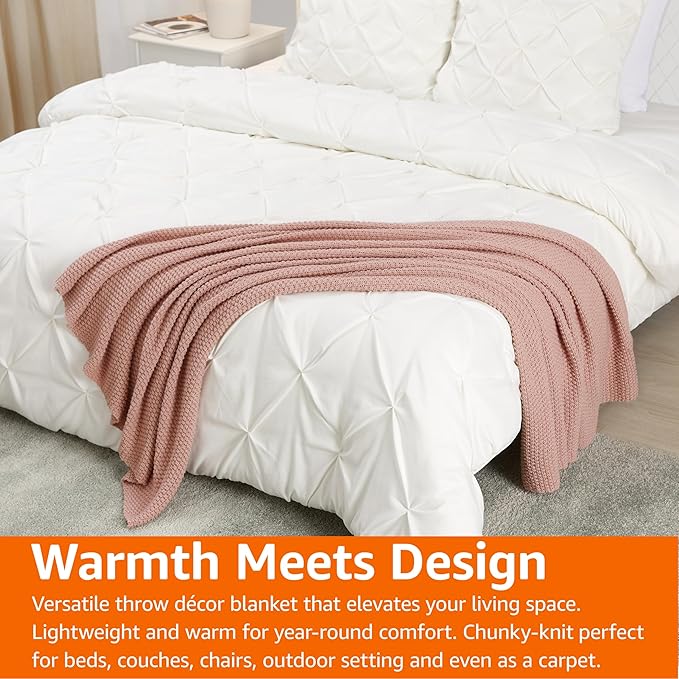 Dusty rose chunky cable knit throw blanket layered over a bed