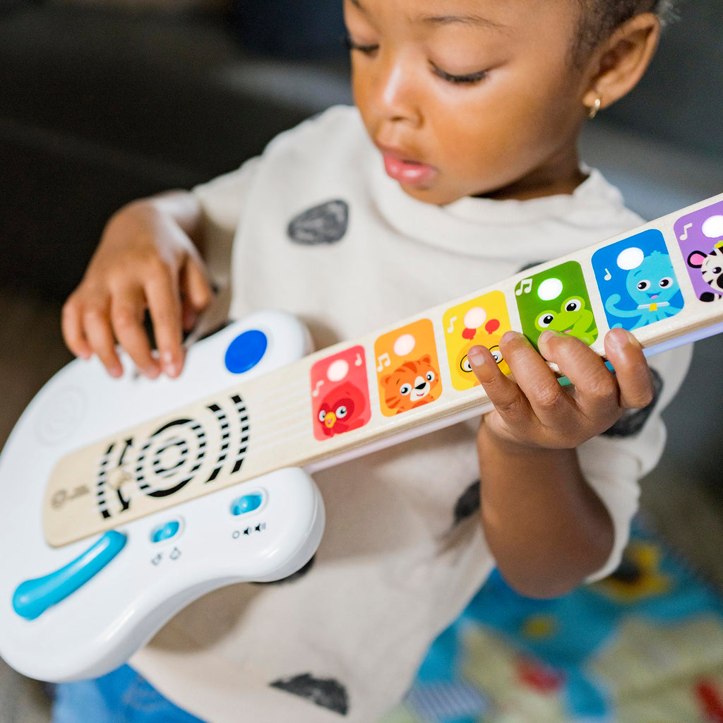 Child playing light-up wooden strum-along guitar with colorful animal keys and blue controls
