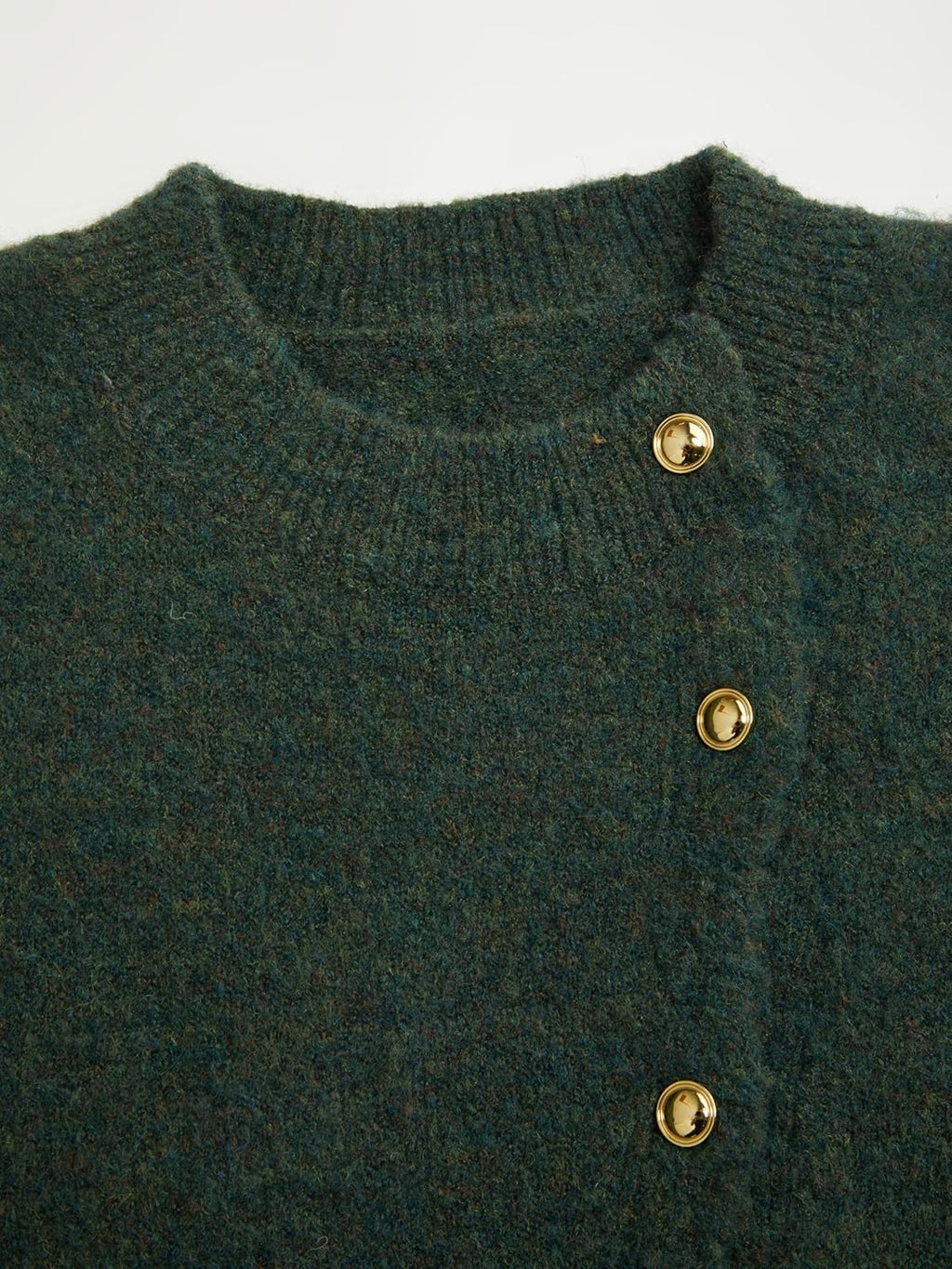 Close-up of dark green knit cardigan neckline and gold snap button placket
