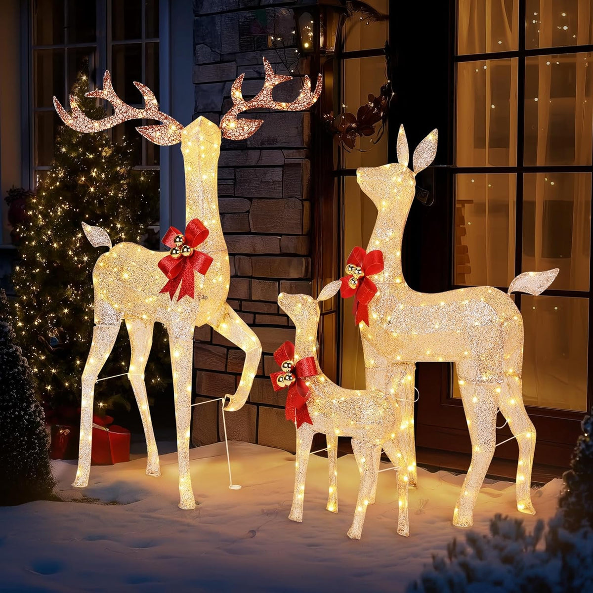 Glowing golden LED reindeer family with red bows on an outdoor patio walkway