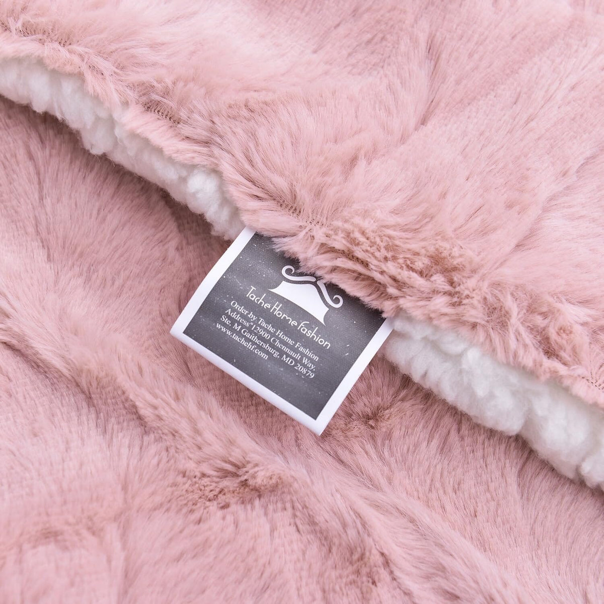 Dusty pink faux fur throw blanket with white trim and fabric brand tag