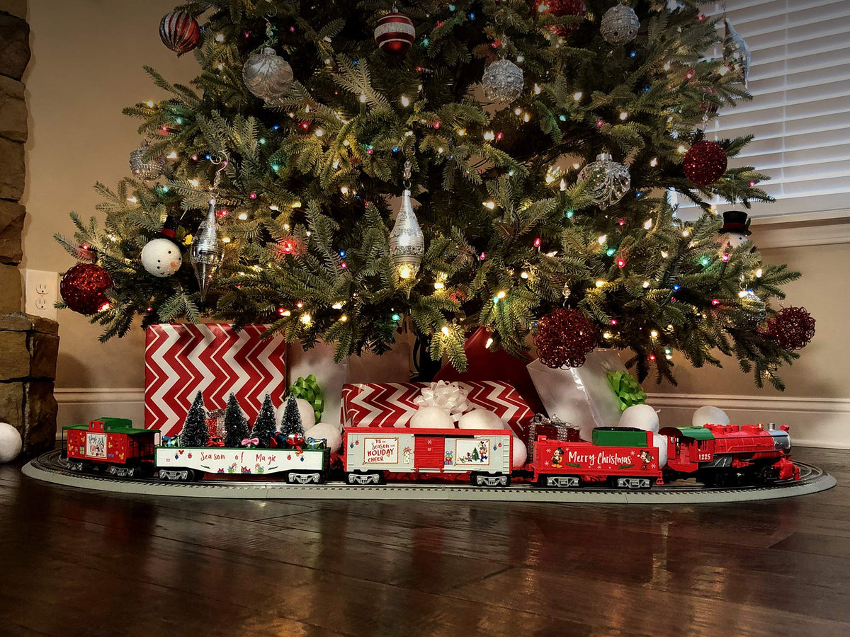 Christmas train set with red cars and decorated tracks on living room floor