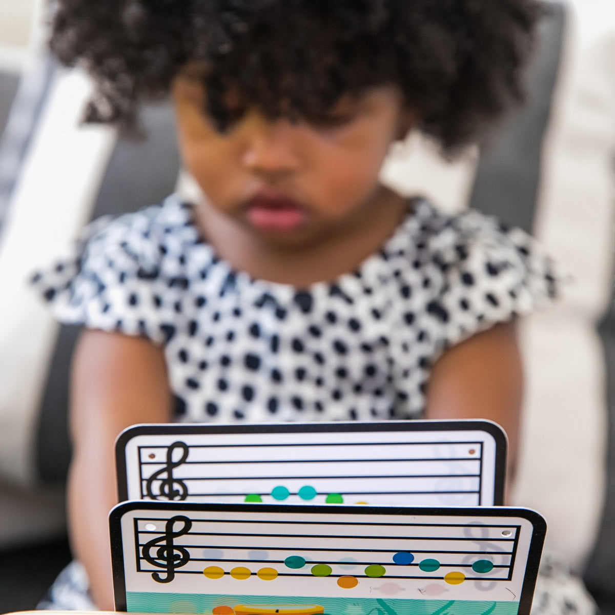 Baby holding two music cards with staff notes from the learning piano