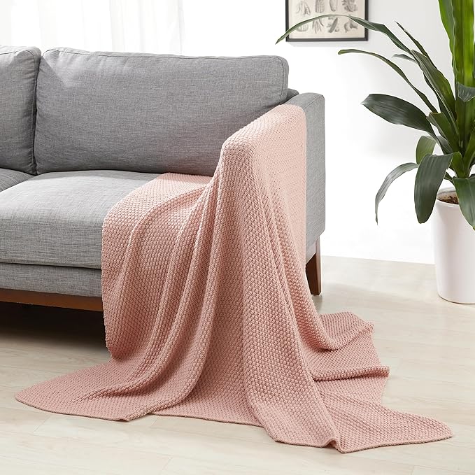 Dusty rose chunky cable knit throw blanket draped over a couch arm