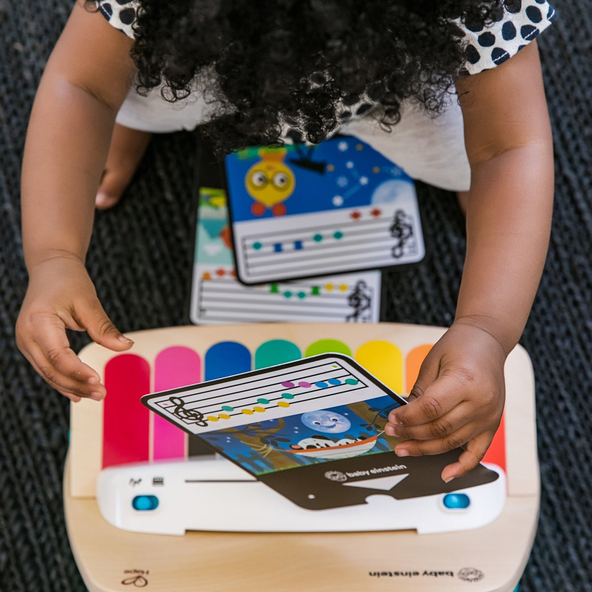 Hands holding musical cards in a wooden baby music piano