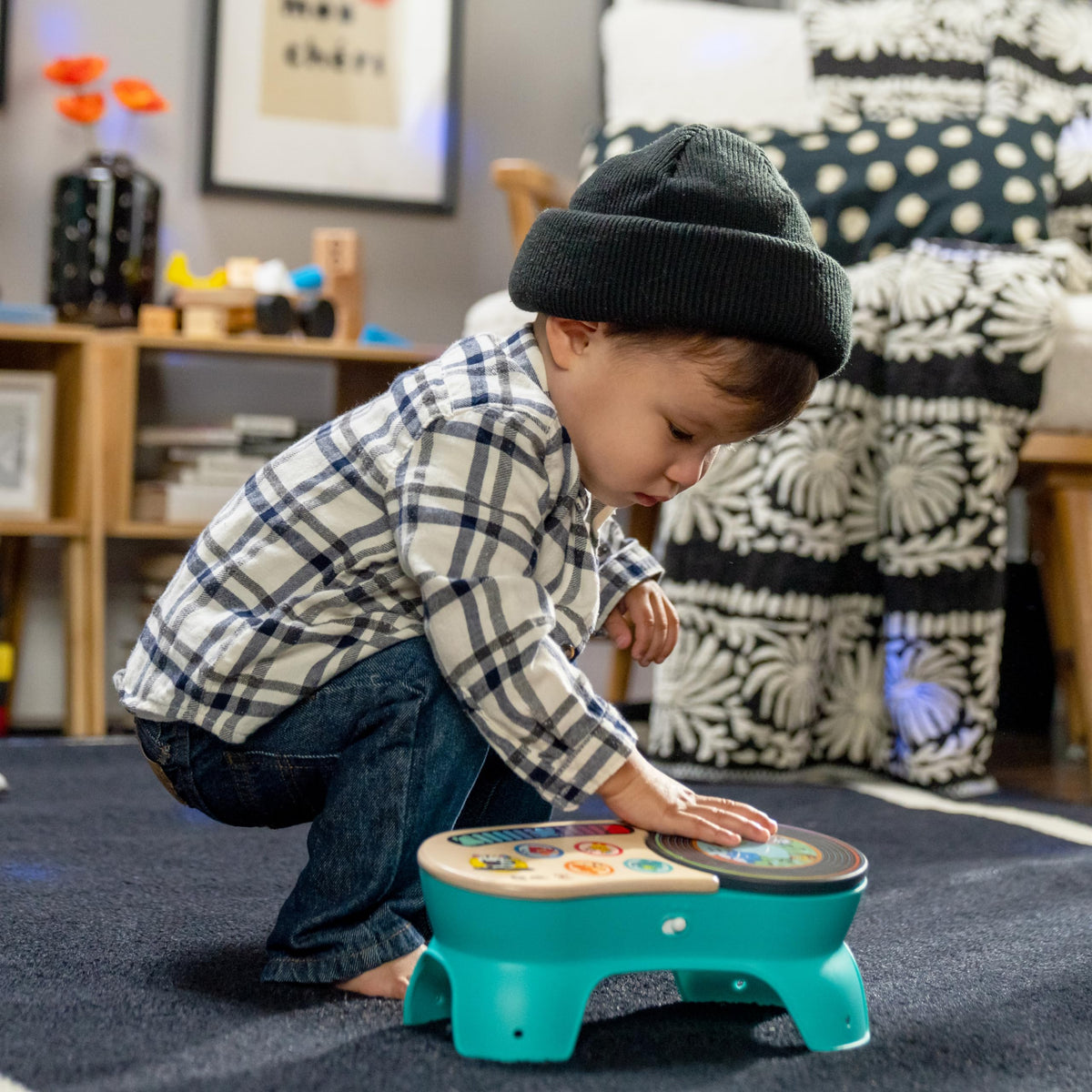 Toddler using a teal discovery stool with wooden top and colorful picture buttons