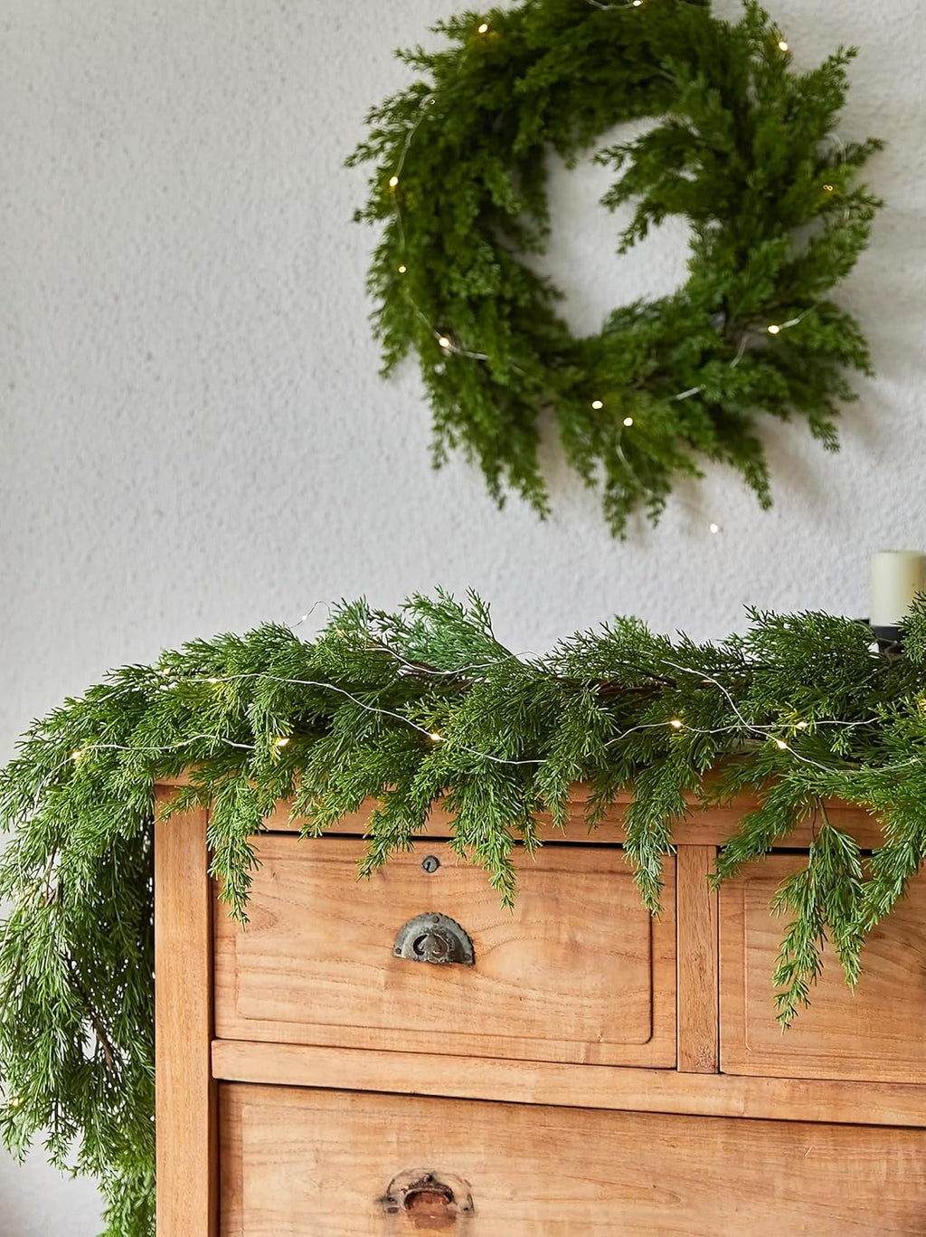 Artificial garland wreath-style loop with warm LED lights and pine needle texture, on wall